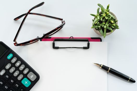 Business objects, clipboard with blank sheet of paper, pen, glasses and calculator on white background