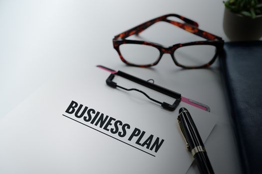 Business plan concept, pen and clipboard with word Business plan, glasses and diary book on white background with copy space