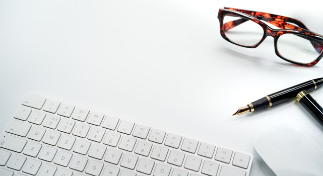 Computer Keyboard and Mouse with Various Office Supplies on white Desk with Copy Space