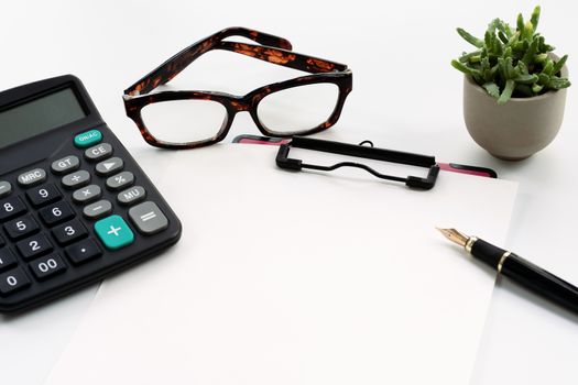 Business objects, clipboard with blank sheet of paper, pen, glasses and calculator on white background