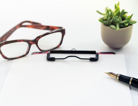 Business objects, clipboard with blank sheet of paper, pen, glasses on white background