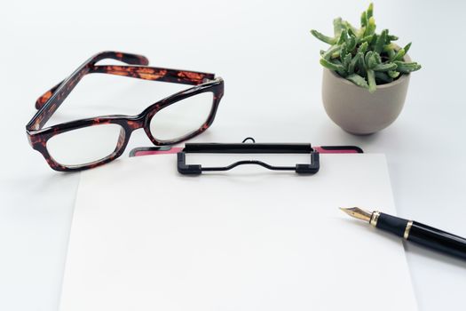 Business objects, clipboard with blank sheet of paper, pen, glasses on white background