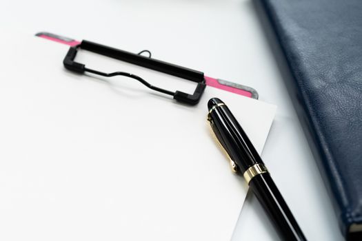 pen and clipboard with blank sheet, glasses on diary book on white background with copy space