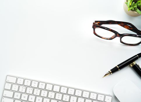 Computer Keyboard and Mouse with Various Office Supplies on white Desk with Copy Space