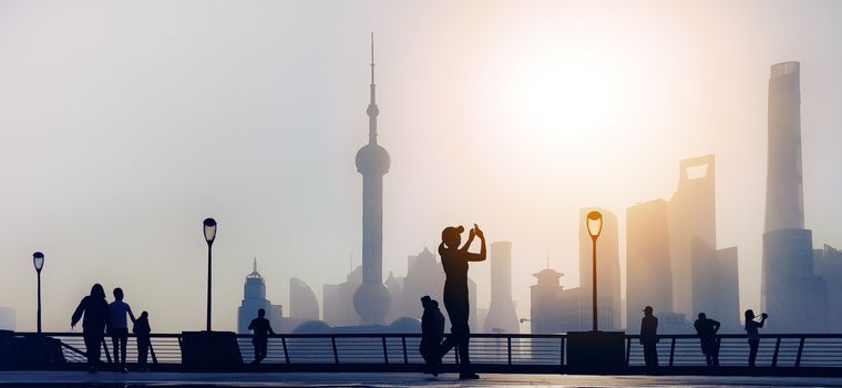 traveler take a photo of morning activity at the bund, huangpu riverside,  shanghai city view background