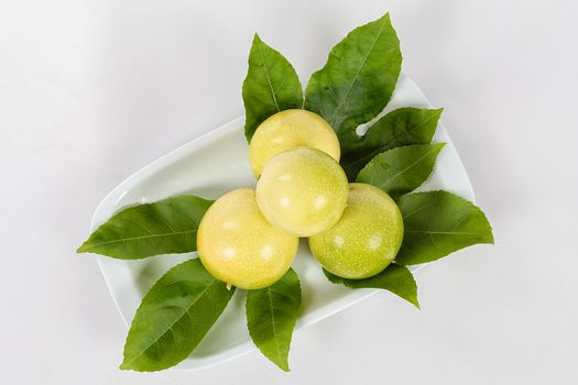 A group of four passion fruit in a bowl on a white background