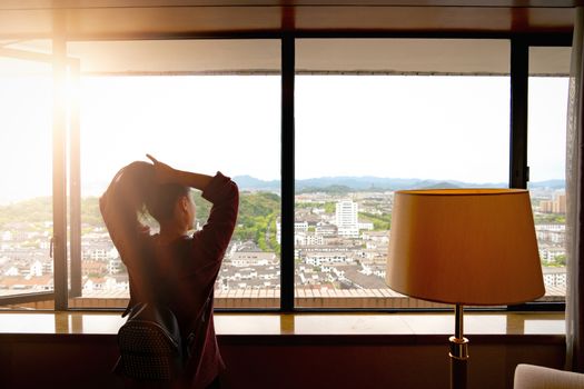 Woman tight hair ready while looking at view from window