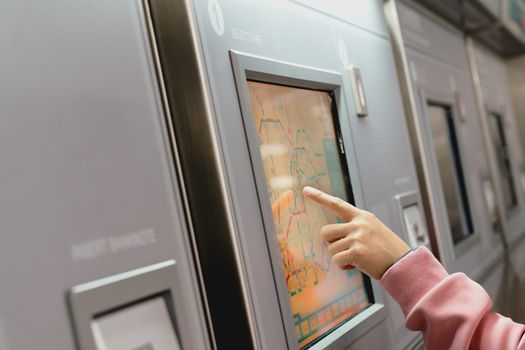 Woman choosing the destination on subway train ticket machine. Transportation concept