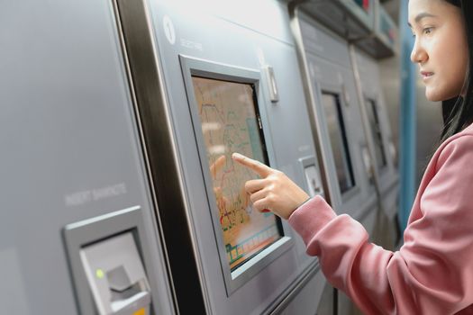 Woman choosing the destination on subway train ticket machine. Transportation concept