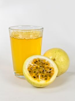 A crystal glass with maracuya juice and a maracuya fruit chopped in half on white background