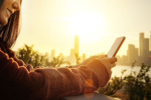 Woman texting on smartphone beside the river in summer season