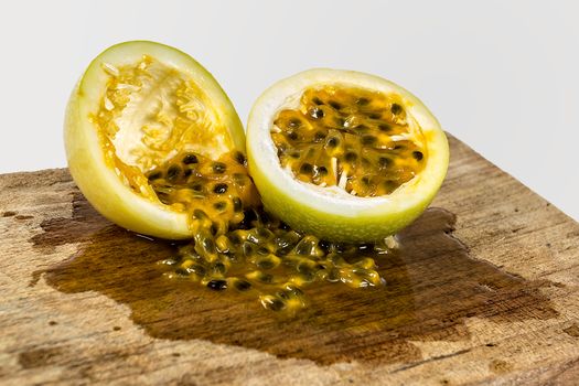 Two halve of a passion fruit one empty and other full of seeds in a piece of wood