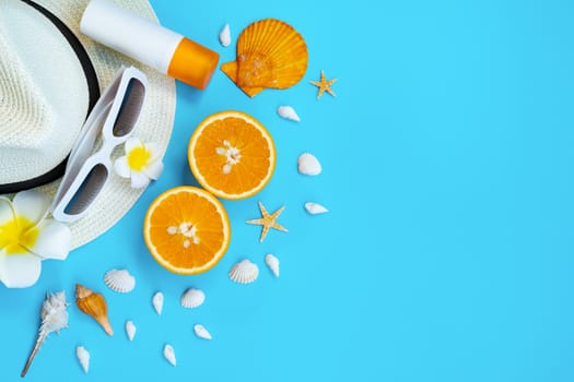 Beautiful summer holiday, Beach accessories, sunglasses, hat, orange, sunblock and shells on blue backgrounds
