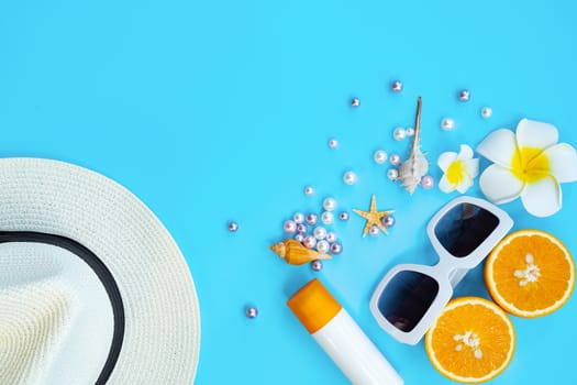 Beautiful summer holiday, Beach accessories, sunglasses, hat, orange, sunblock and shells on blue backgrounds