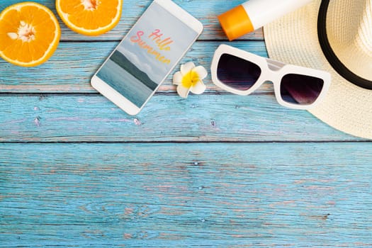 Beautiful summer holiday, Beach accessories, orange, sunglasses, hat, sunblock and smartphone on wooden backgrounds