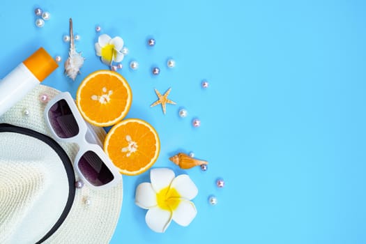 Beautiful summer holiday, Beach accessories, sunglasses, hat, orange, sunblock and shells on blue backgrounds