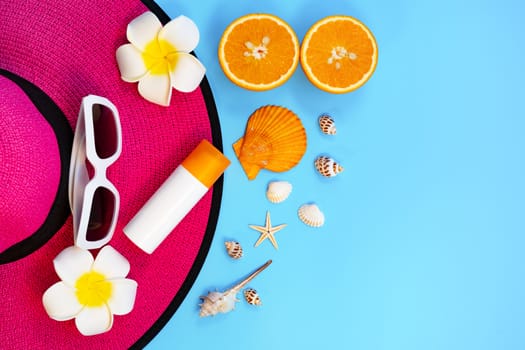 Beautiful summer holiday, Beach accessories, sunglasses, hat, orange, sunblock and shells on blue backgrounds