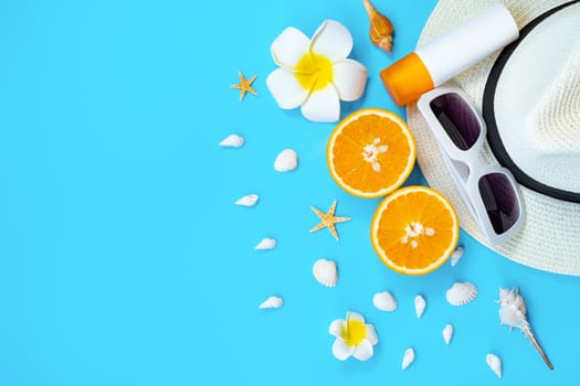 Beautiful summer holiday, Beach accessories, sunglasses, hat, orange, sunblock and shells on blue backgrounds