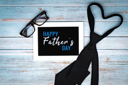 Happy fathers day greeting card with necktie and glasses on wooden table, Flat lay style