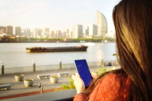 Woman texting on smartphone beside the river in summer season