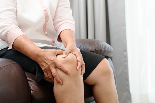 senior woman suffering from knee pain at home, health problem concept