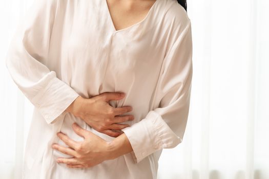 Young woman suffering from abdominal pain feeling stomachache, symptom of pms on white background