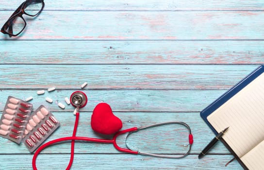 healthcare and medical concept red stethoscope and medicine on the blue wooden background