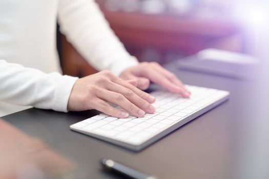 financial advisor typing on keyboard while sitting at office and working on computer - filter applied