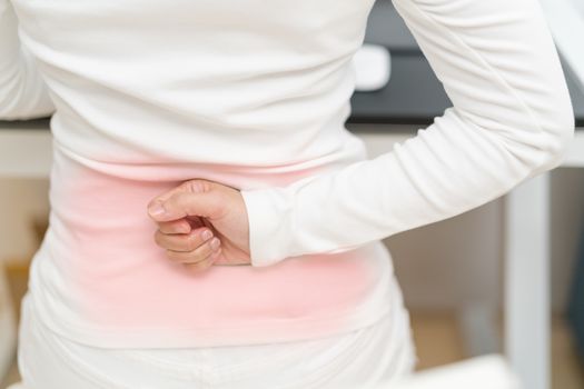 young woman with back pain working with computer. Healthcare and medical concept