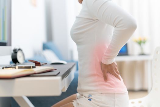 young woman with back pain working with computer. Healthcare and medical concept