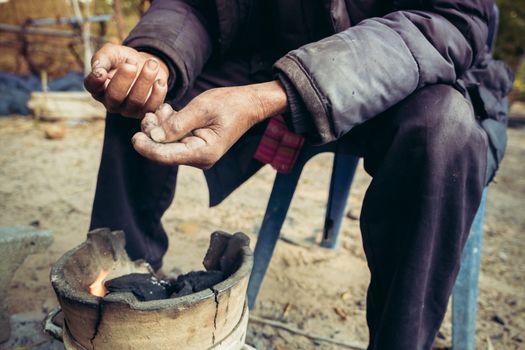 portrait old man on rural of Thailand in winter season with the small fireplace - gain noise filter applied