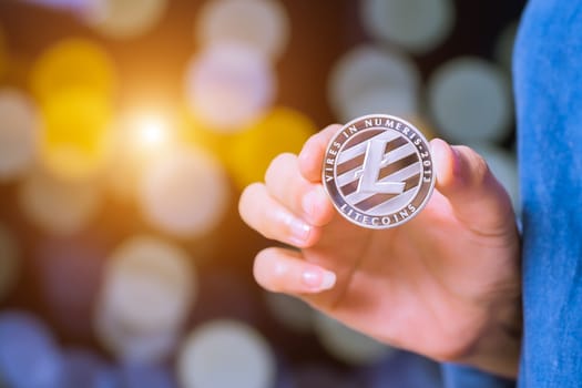 cryptocurrency coins - Litecoin, Ethereum, Bitcoin, Ripple. Women hold the cryptocurrency coin on hand. Physical bitcoins gold and silver coins