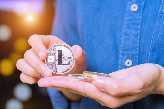 cryptocurrency coins - Litecoin, Ethereum, Bitcoin, Ripple. Women hold the cryptocurrency coin on hand. Physical bitcoins gold and silver coins