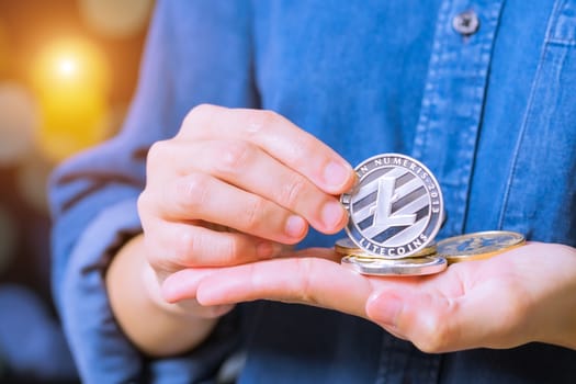 cryptocurrency coins - Litecoin, Ethereum, Bitcoin, Ripple. Women hold the cryptocurrency coin on hand. Physical bitcoins gold and silver coins