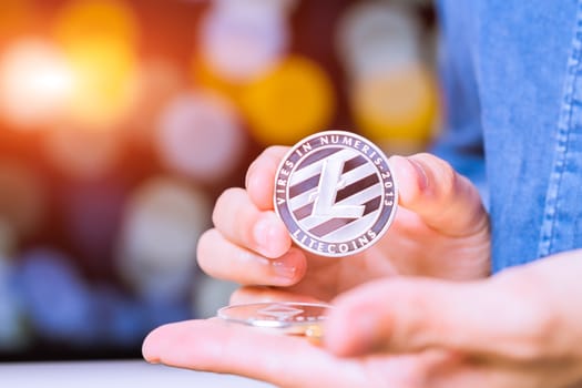 cryptocurrency coins - Litecoin, Ethereum, Bitcoin, Ripple. Women hold the cryptocurrency coin on hand. Physical bitcoins gold and silver coins