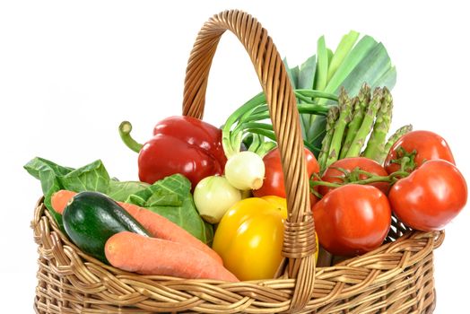 Healthy eating concept - basket full of varied fresh vegetables: asparagus, tomatoes, leek, onion, paprika, cabbage, carrot and zucchini,