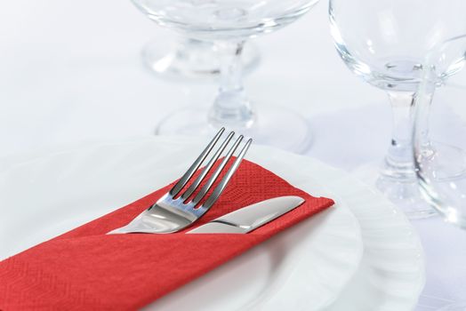 Elegant table setting in the restaurant: cutlery in a red napkin on the plates and next to the wine glasses