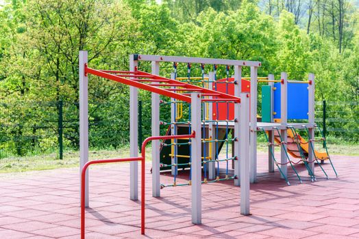 Children's playground in a public park or outside a kindergarten on the background of green trees