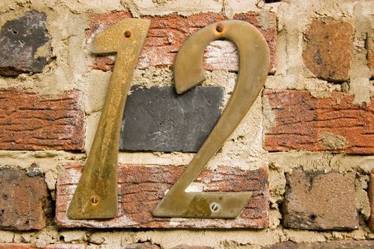 Number 12 on an old brick wall on the outside of a house.