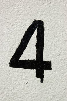 The number four painted rather roughly in black on a white wall.