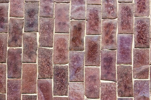 Close up of a wall covered in purple mosaic ceramic tiles.