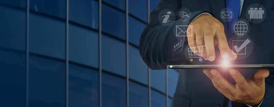 Banner - concept of modern digital management - businessman holds in his hand a digital tablet and manages the various divisions of the corporation through the hologram.