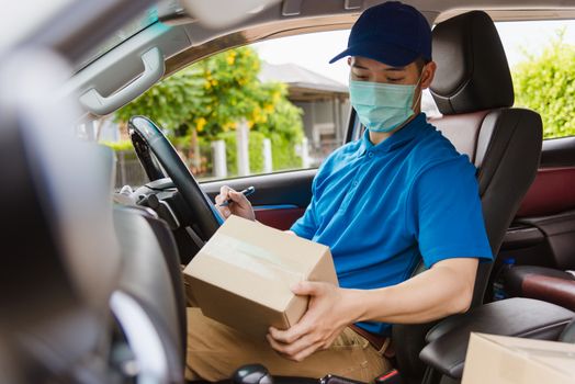 Asian delivery courier young man driver inside the van car with parcel post boxes checking amount he protective face mask, under curfew quarantine pandemic coronavirus COVID-19