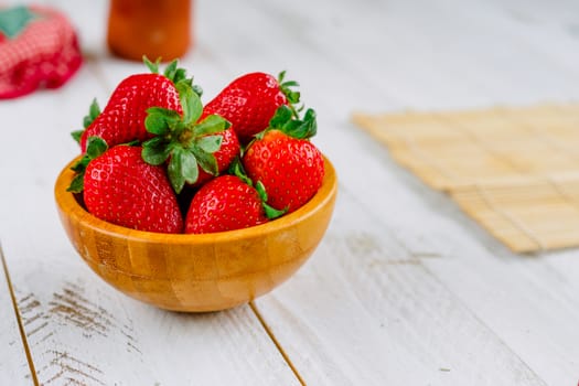 Organic strawberries on a bowl on a white wooden table much colorful