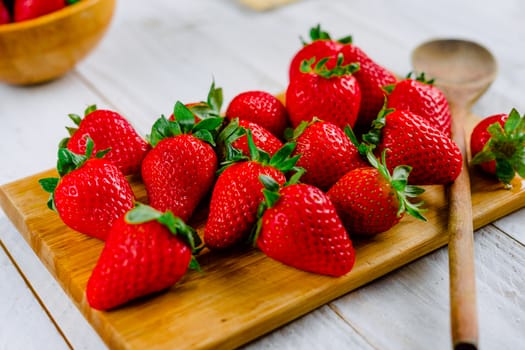 Organic strawberries on a cutting board fruit on a white wooden table