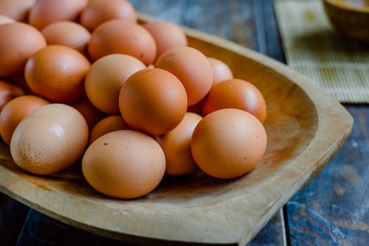 Organic eggs in a large wooden bowl on a wooden table