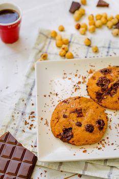 Organic chocolate chip cookies with hazelnuts and coffee in a square plate on a wooden table