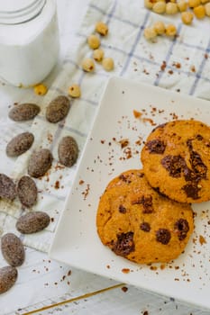 Organic chocolate chip cookies with hazelnuts and coconut milk in a square plate on a wooden table