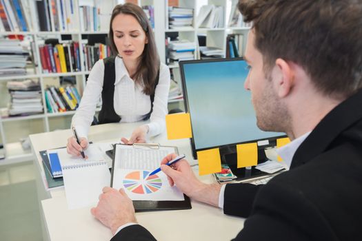 Young business people studying statistics data in office