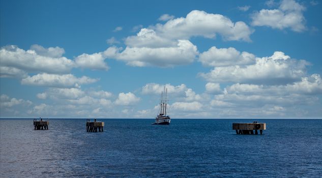 A three masted sailboat moored in a calm blue bay